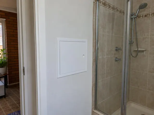 Small white access panel in a painted wall beside a tiled shower in Wetherill Park